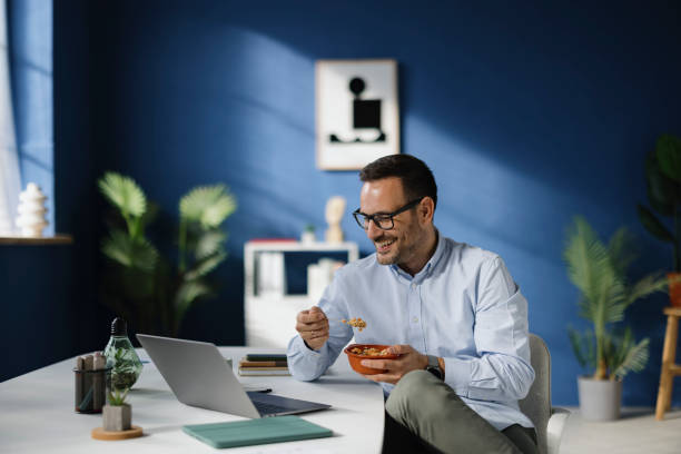 Person sitting thoughtfully at a desk with a notebook and a healthy meal on the side